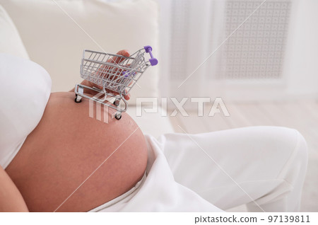 Faceless pregnant woman holding a shopping cart on her belly. Faceless pregnant woman holding a shopping cart on her belly. 97139811