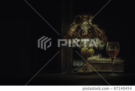 A glass of red wine puts on dressing table in the dim light of Vintage night lamp. 97140454