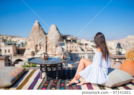 Happy young woman during vacation watching hot air balloons in Cappadocia, Turkey Happy young woman during vacation watching hot air balloons in Cappadocia, Turkey 97141881