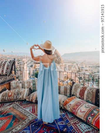 Young woman in dress on the roof with amazing view of Cappadocia in Turkey Young woman in dress on the roof with amazing view of Cappadocia in Turkey 97141915