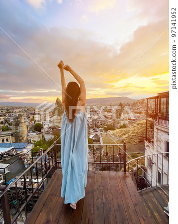 Young woman in dress on the roof with amazing view of Cappadocia in Turkey 97141952