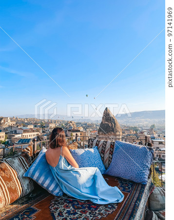 Young woman in dress on the roof with amazing view of Cappadocia in Turkey Young woman in dress on the roof with amazing view of Cappadocia in Turkey 97141969