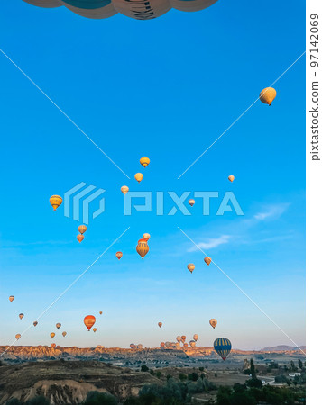 Hot air balloon flying over rocky landscapes in Cappadocia with beautiful sky on background 97142069