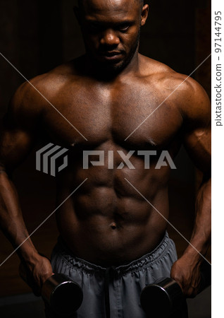 Muscular dark-skinned man doing an exercise with dumbbells. Muscular dark-skinned man doing an exercise with dumbbells. 97144795
