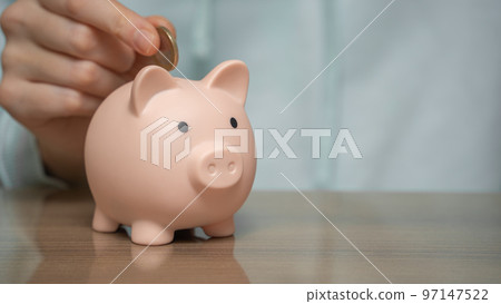 Female hands puts a coin in a piggy bank close-up. Female hands puts a coin in a piggy bank close-up. 97147522
