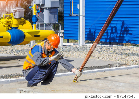 Slinger lays concrete slab on construction site on summer day. Worker in protective vest and 97147543