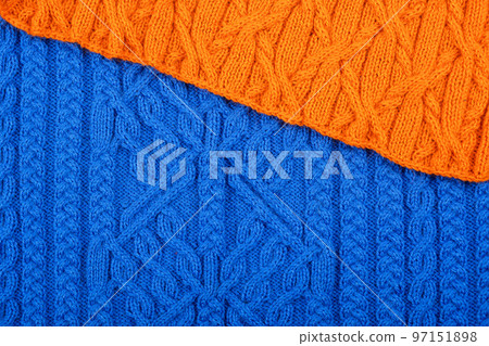 Knitted blue and orange background. Large knitted fabric with a pattern. Close-up of a knitted blanket. Knitted blue and orange background. Large knitted fabric with a pattern. Close-up of a knitted blanket. 97151898