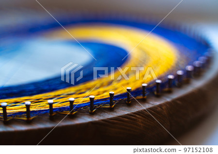 Colored thread mandala on a wooden board with nails. Mandala Moon Harmony Sun esotericism and psychology pictures from yellow and blue silk threads. 97152108