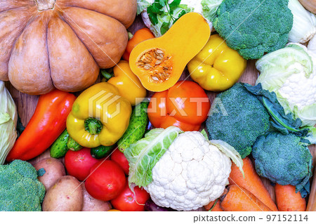 Various vegetables are laid out on a wooden table. Large assortment of vegetables food. pumpkin cabbage broccoli pepper tomatoes carrots and others 97152114
