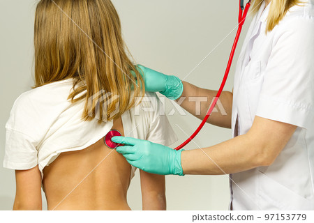 Little girl at the family doctor. lung area examined with stethoscope. Pediatrician checks the health, listens to the child with a Stethoscope. Little girl at the family doctor. lung area examined with stethoscope. Pediatrician checks the health, listens to the child with a Stethoscope. 97153779