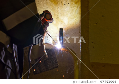 Professional welder welding with electric old metal pipes for heating. Old heating system renovation concept Professional welder welding with electric old metal pipes for heating. Old heating system renovation concept 97153994