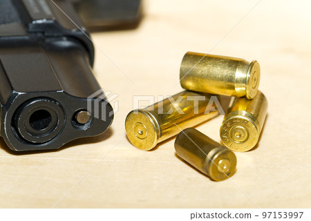 shell casings and barrel of a pistol close-up on a wooden table in a shooting range or at a crime scene. crime concept shell casings and barrel of a pistol close-up on a wooden table in a shooting range or at a crime scene. crime concept 97153997
