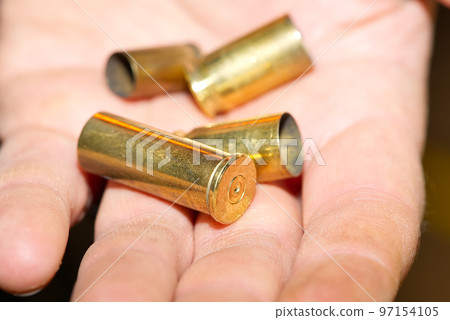close-up of bronze cartridge cases on a hand in a shooting range or at a crime scene. crime concept 97154105