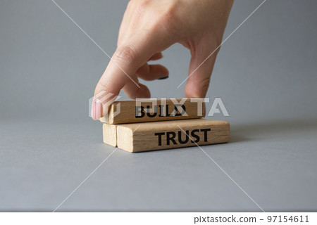 Build trust symbol. Wooden blocks with words Build trust. Beautiful grey background. Businessman hand. Business and Build trust concept. Copy space. Build trust symbol. Wooden blocks with words Build trust. Beautiful grey background. Businessman hand. Business and Build trust concept. Copy space. 97154611