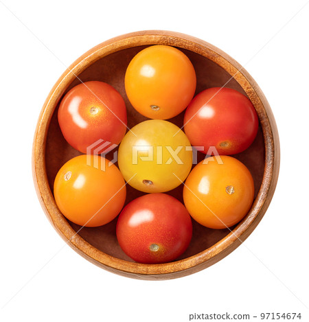 Colorful cherry tomatoes, in a wooden bowl. Fresh and ripe type of small and round cocktail tomatoes, of red, yellow and orange color. Solanum lycopersicum var. cerasiforme. Close-up, from above. 97154674