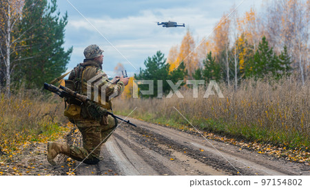 Photo of a mercenary soldier launch a reconnaissance drone on the road in a forest. Photo of a mercenary soldier launch a reconnaissance drone on the road in a forest. 97154802