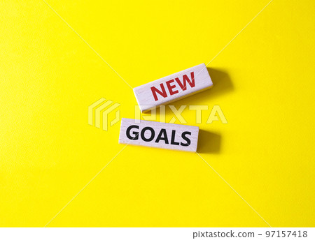 New goals symbol. Wooden blocks with words New goals. Beautiful yellow background. Business and New goals concept. Copy space. 97157418