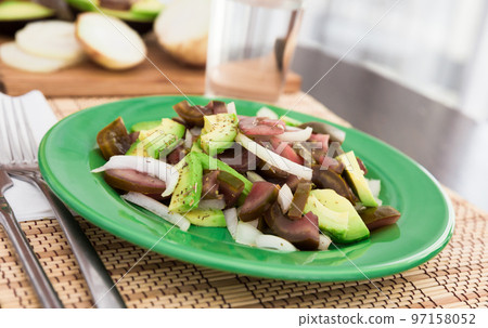 salad of black tomatoes, avocado and onions on green plate salad of black tomatoes, avocado and onions on green plate 97158052