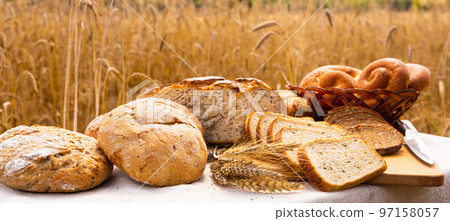 lot of different flavored bread, wheat, rye, on the table in the field outside lot of different flavored bread, wheat, rye, on the table in the field outside 97158057