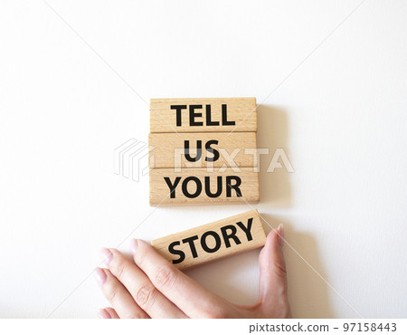 Tell us your story symbol. Concept words Tell us your story on wooden blocks. Beautiful white background. Businessman hand. Business and Tell us your story concept. Copy space. 97158443