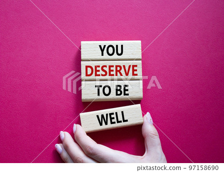 You deserve to be well symbol. Wooden blocks with words You deserve to be well. Beautiful red background. Businessman hand. You deserve to be well concept. Copy space. 97158690