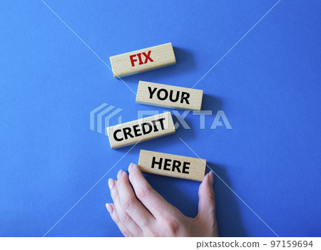 Fix your credit here symbol. Concept words Fix your credit here on wooden blocks. Beautiful blue background. Businessman hand. Business and Fix your credit here concept. Copy space. 97159694