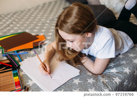The girl after school plays at home, draws with pencils and felt-tip pens 97159766
