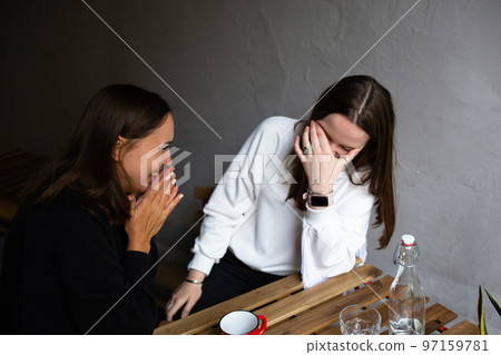 Two young women girlfriends communicate and have fun in a street cafe Two young women girlfriends communicate and have fun in a street cafe 97159781