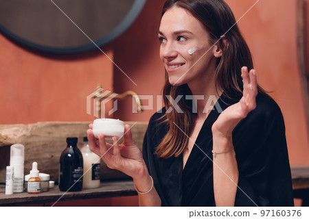 Young woman puts cream on her face 97160376