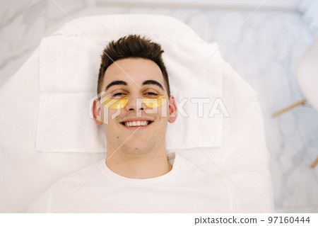 Handsome man with golden patch under eyes. Beauty studio. Spa salon. Top view Handsome man with golden patch under eyes. Beauty studio. Spa salon. Top view 97160444