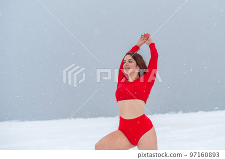 Caucasian woman dressed in shorts and a top goes in for sports outdoors in winter. 97160893