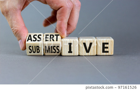 Submissive or assertive symbol. Concept words Submissive and assertive on wooden cubes. Businessman hand. Beautiful grey background. Business, psychological submissive assertive concept. Copy space. Submissive or assertive symbol. Concept words Submissive and assertive on wooden cubes. Businessman hand. Beautiful grey background. Business, psychological submissive assertive concept. Copy space. 97161526
