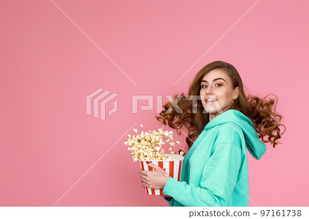 woman holding bucket of popcorn and jumping 97161738