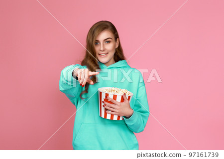 woman in sweatshirt watching movie film, eating popcorn woman in sweatshirt watching movie film, eating popcorn 97161739