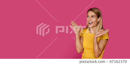 Cheerful shocked mature caucasian blonde lady in yellow t-shirt with open mouth looking at free space Cheerful shocked mature caucasian blonde lady in yellow t-shirt with open mouth looking at free space 97162370