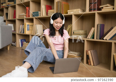 Distance learning. Asian lady in headphones studying with laptop at home, using computer for online education 97162390