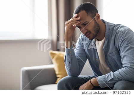 Portrait Of Depressed Young Black Man Sitting On Couch At Home 97162525
