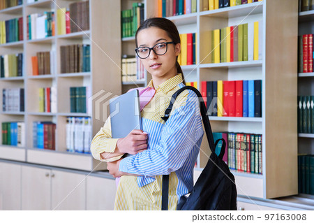 Portrait of teenager student girl looking at camera in library Portrait of teenager student girl looking at camera in library 97163008