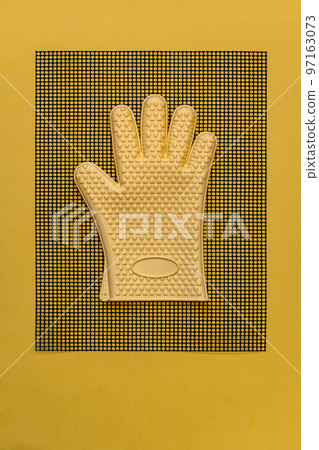 Yellow heat resistant glove on kitchen mesh mat 97163073