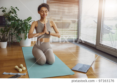 Woman taking online yoga class from home. Female engaged in webcam meditation practice on computer 97163176