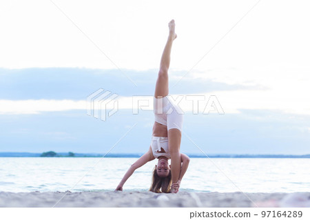 Young woman doing complex Yoga exercise headstand with Namaste asana. 97164289