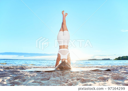 young woman performing yoga exercises. Headstand , inversion. 97164299