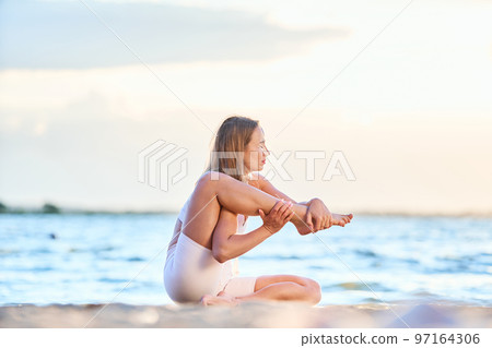 attractive woman practicing yoga by the lake. Downdog downward f 97164306