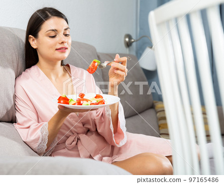 Woman eating salad on sofa 97165486