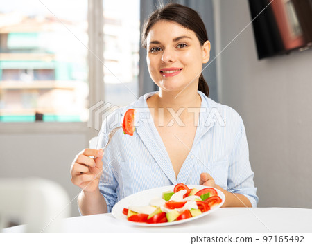 Woman eating salad at table 97165492