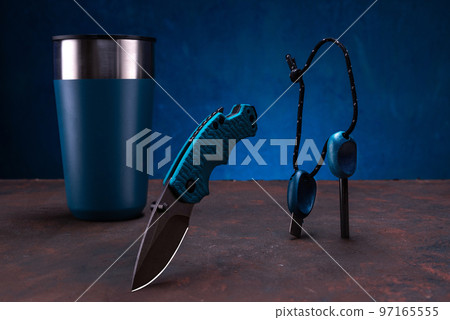 A set of a pocket knife, a thermo glass and a steel for making a fire. Tourist items of the same color. 97165555