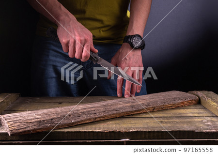 The man holds a sharp knife in his hand. Hit with a sharp knife. Big knife in hand. Attack with a knife. The man holds a sharp knife in his hand. Hit with a sharp knife. Big knife in hand. Attack with a knife. 97165558