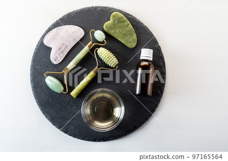 Cosmetic appliances and skin care products on a black tray. Hand tools and stones for massage. Multicolored stones. Cosmetic appliances and skin care products on a black tray. Hand tools and stones for massage. Multicolored stones. 97165564