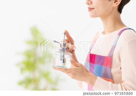 A woman giving water to a plant A woman giving water to a plant 97165880