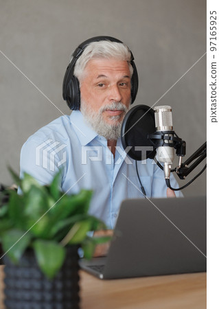 older man with gray hair irecording podcast in recording studio with microphone and headphones older man with gray hair irecording podcast in recording studio with microphone and headphones 97165925